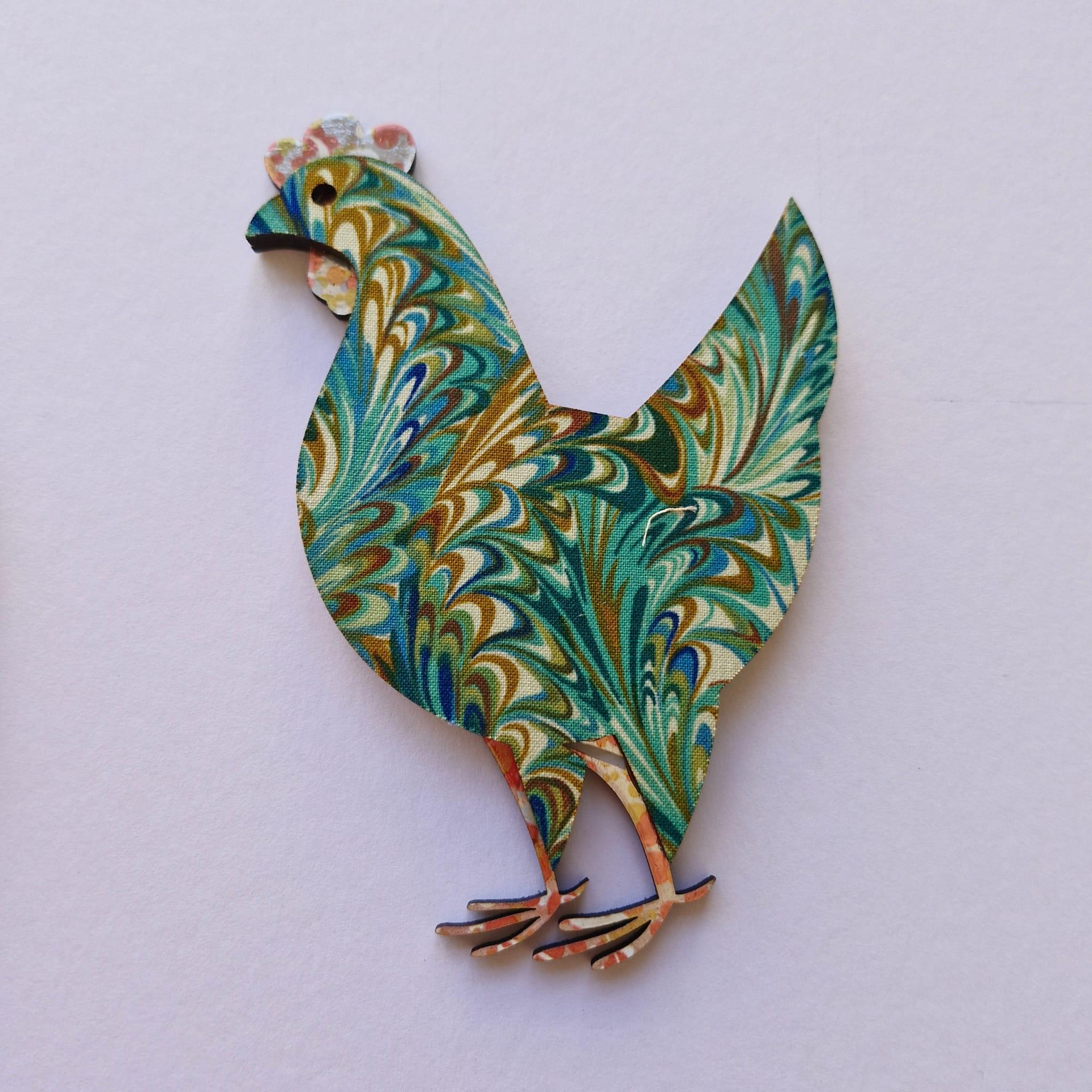 A laser cut rooster decorated with vintage fabric and paper