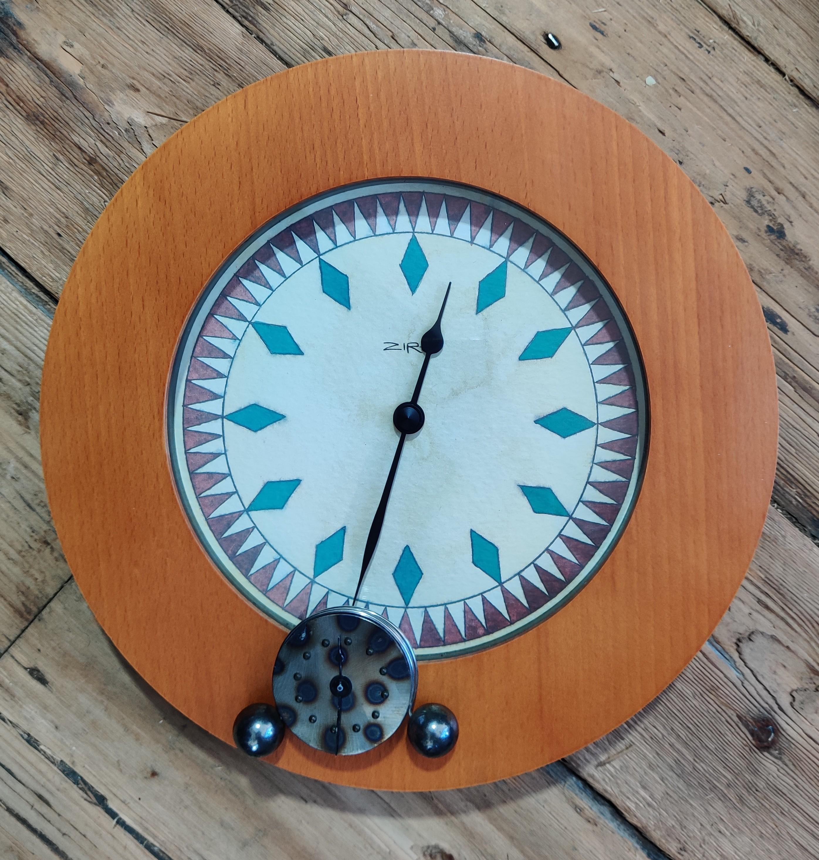 A wooden wall clock and small dark metal mantel clock