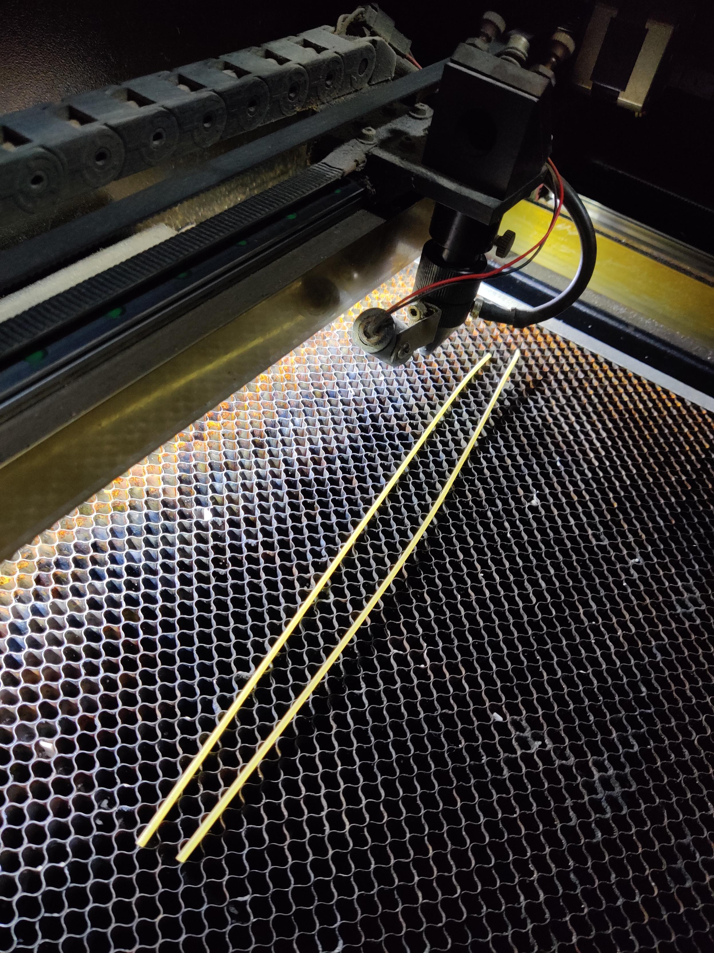 2 pieces of spaghetti on a laser cutter bed