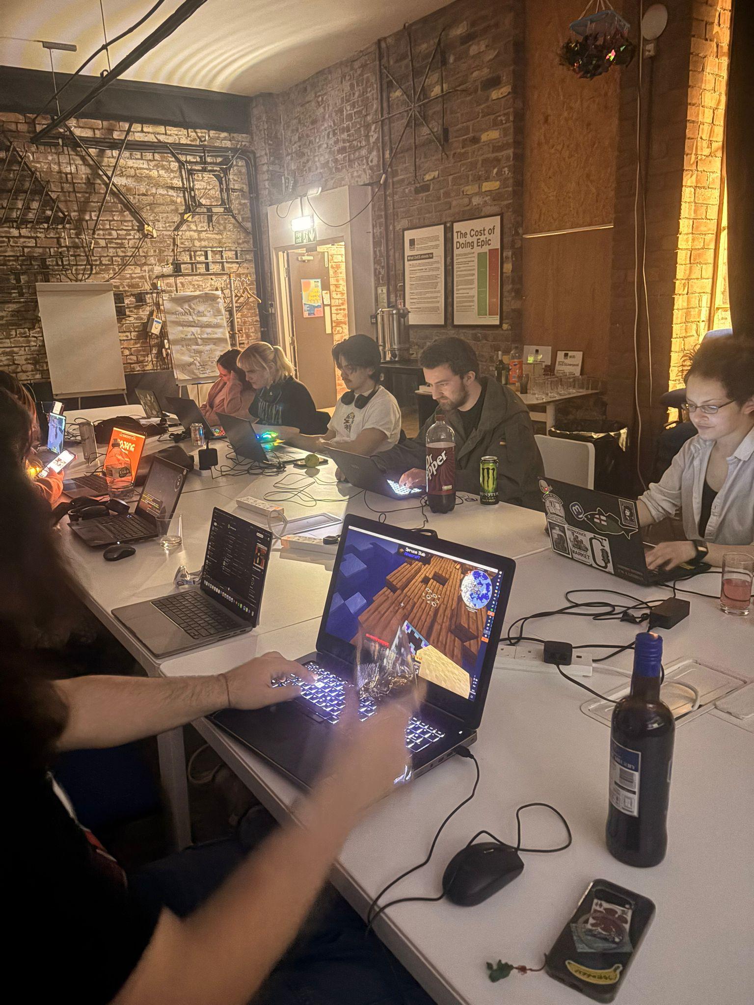 People sitting around a large table with laptops in the DoES Liverpool event space 