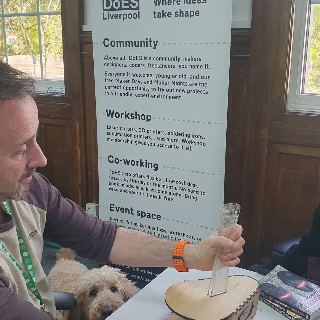 Terry, sitting in front of the DoES Liverpool pull up banner, reassembling his mechanical bird for display