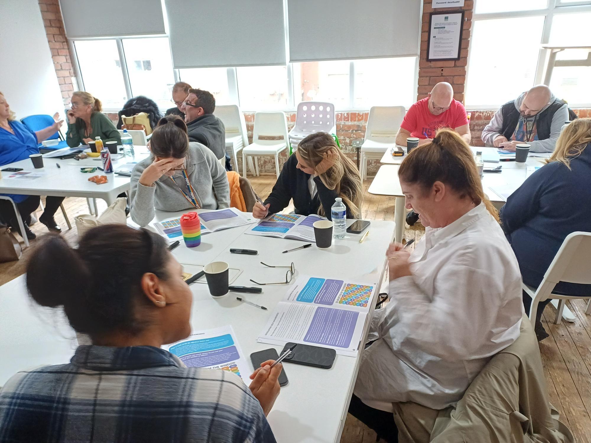 People sitting around tables, working on workbooks 