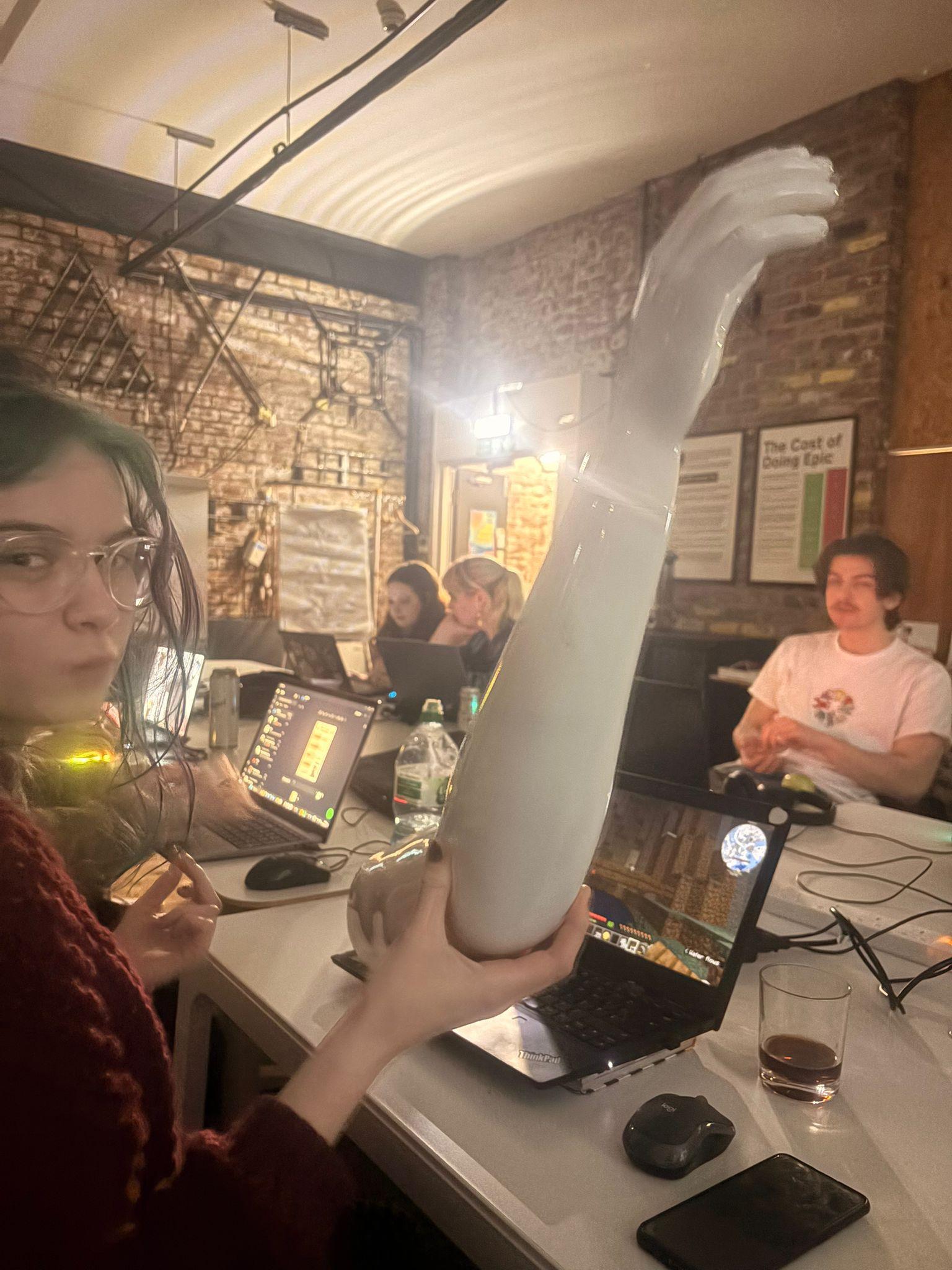 People sitting around a table in the DoES Liverpool Event Space with a large white plastic arm