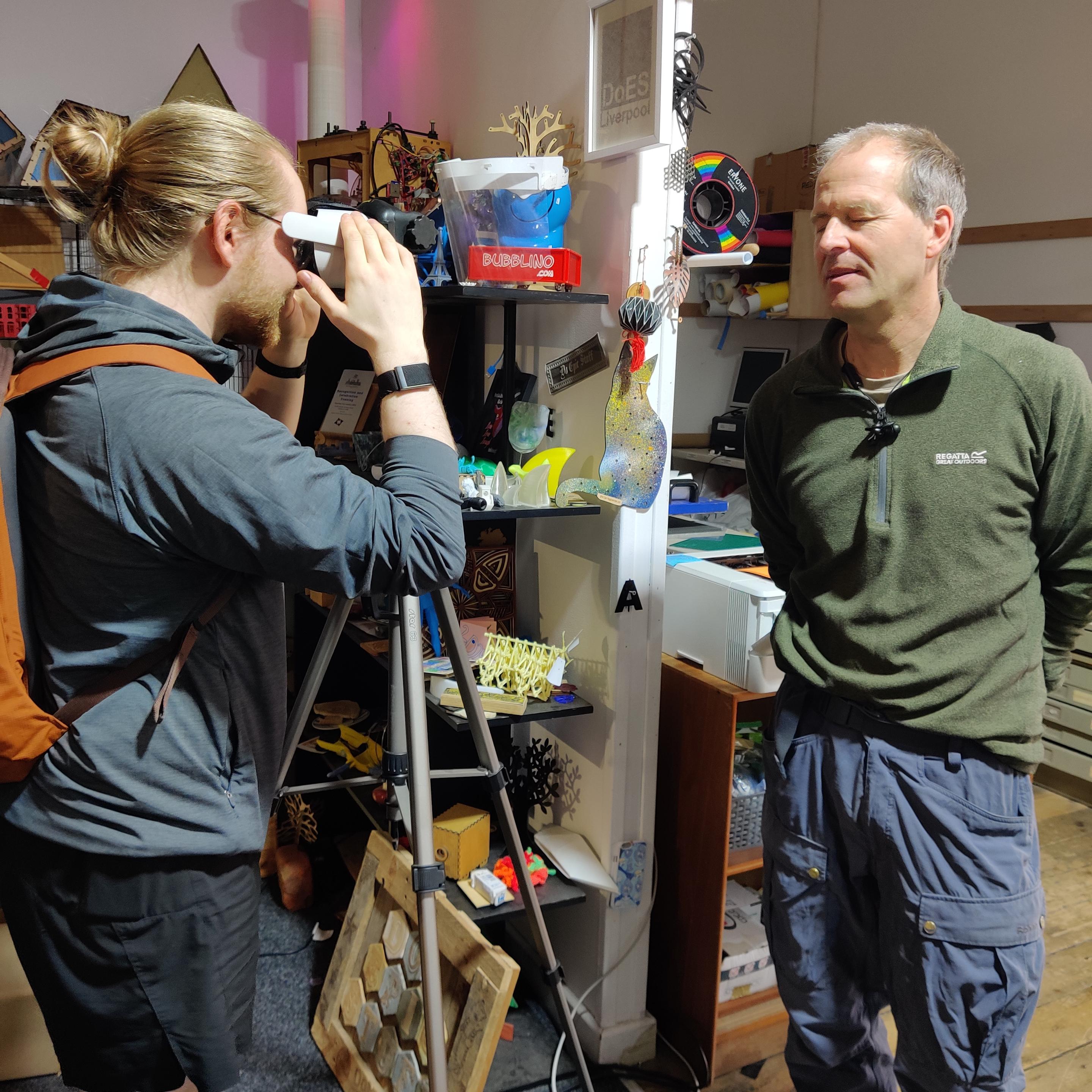 Julian showing a Repair Café visitor how to use a VR headset