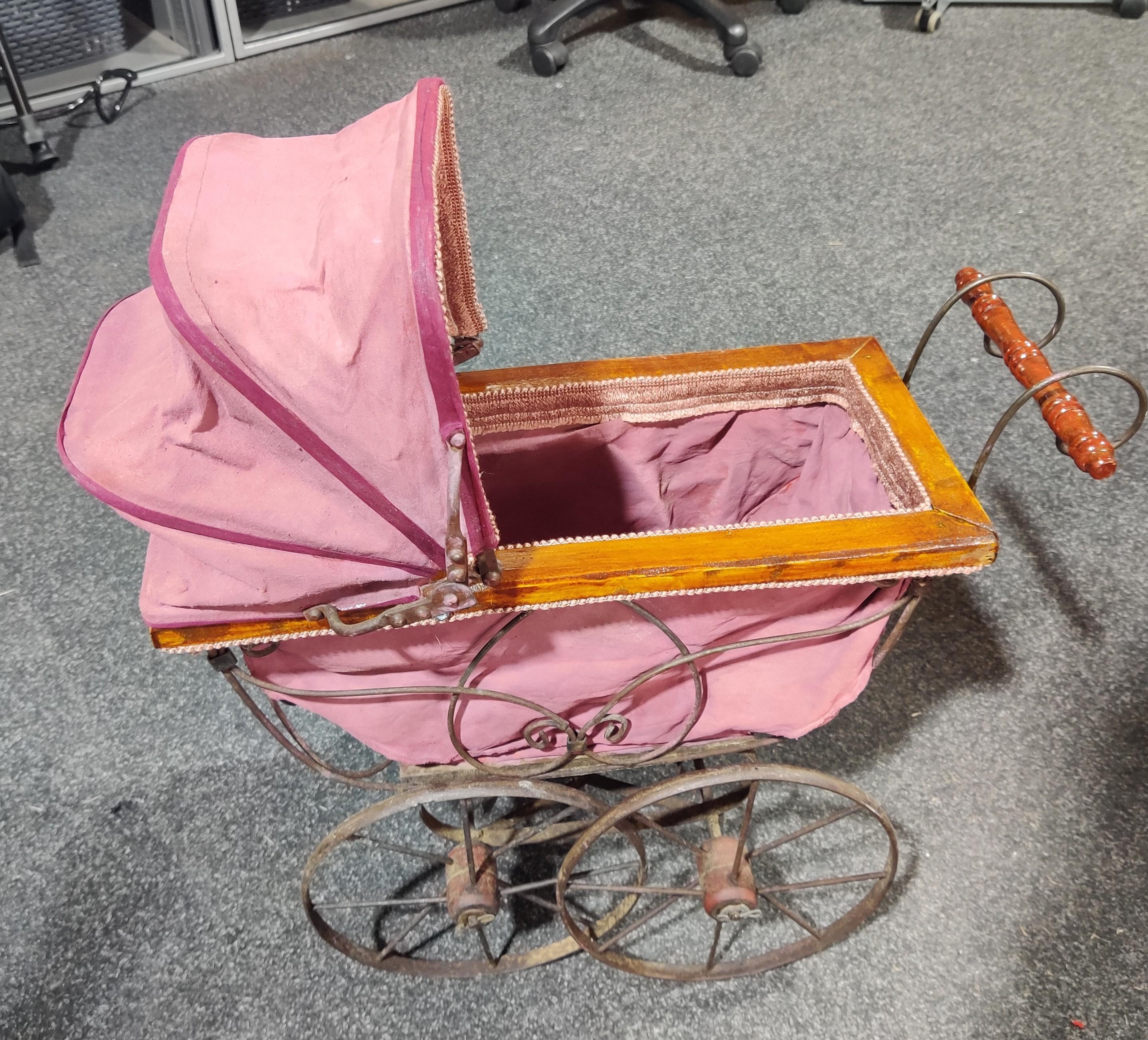 A pink sntique-looking toy pram
