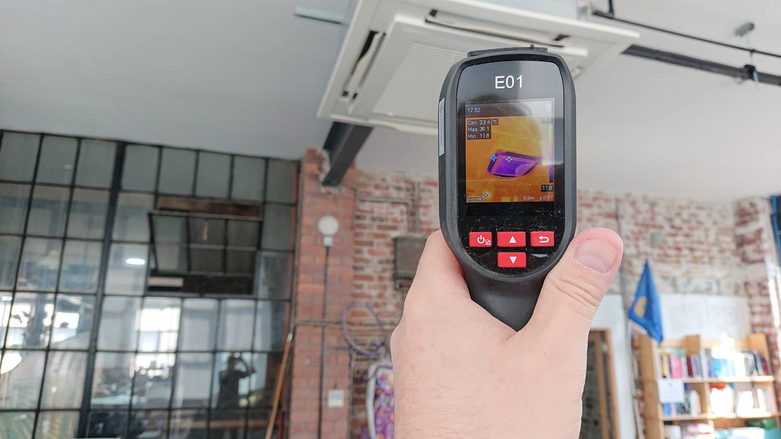 A photo from inside our co-working space. A hand is holding an infrared camera which is pointed at the HVAC unit on the ceiling. On its screen the unit shows up as very cold, as you'd want in this weather.