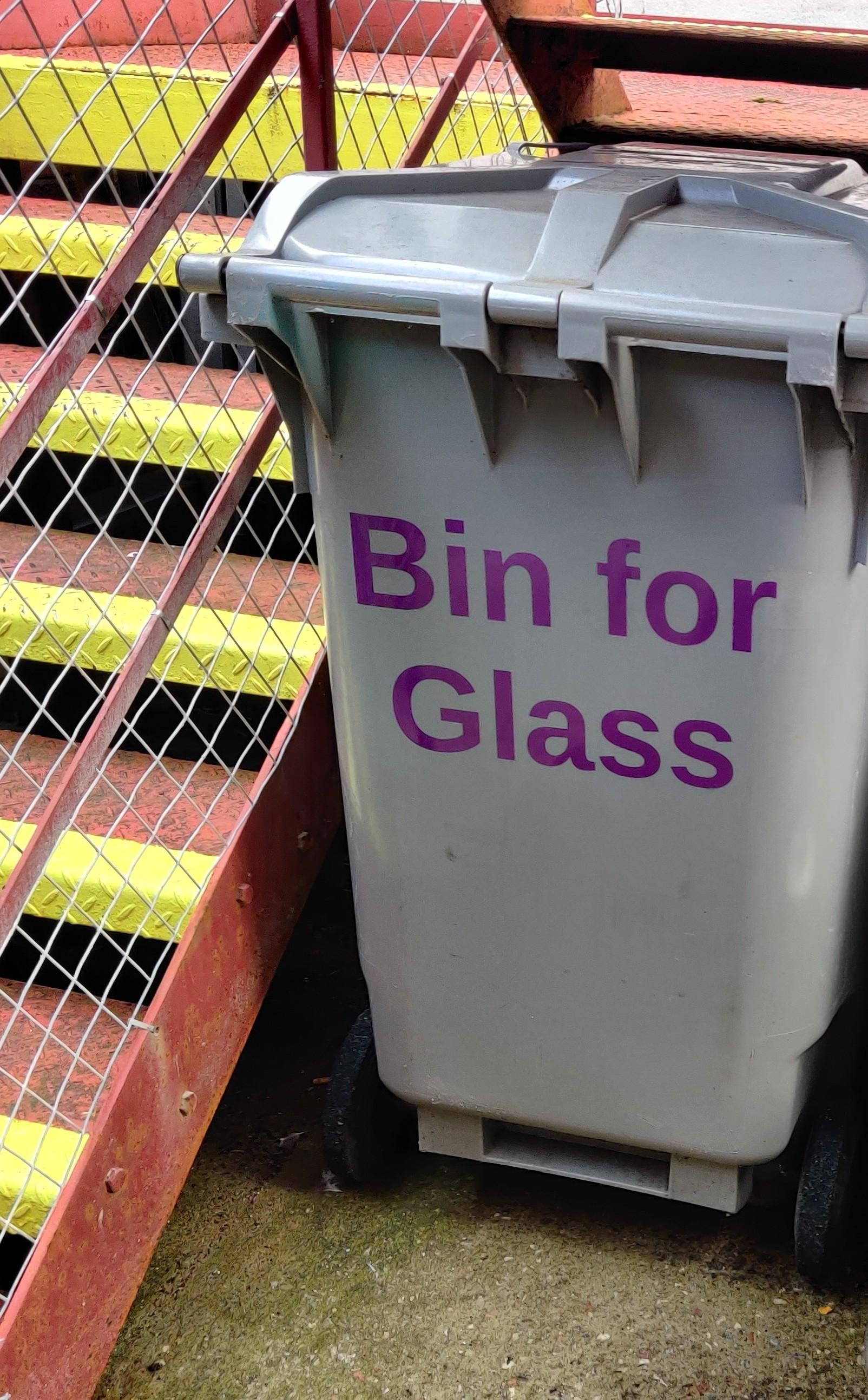 A grey wheelie bin with purple lettering reading 'Bin for Glass'