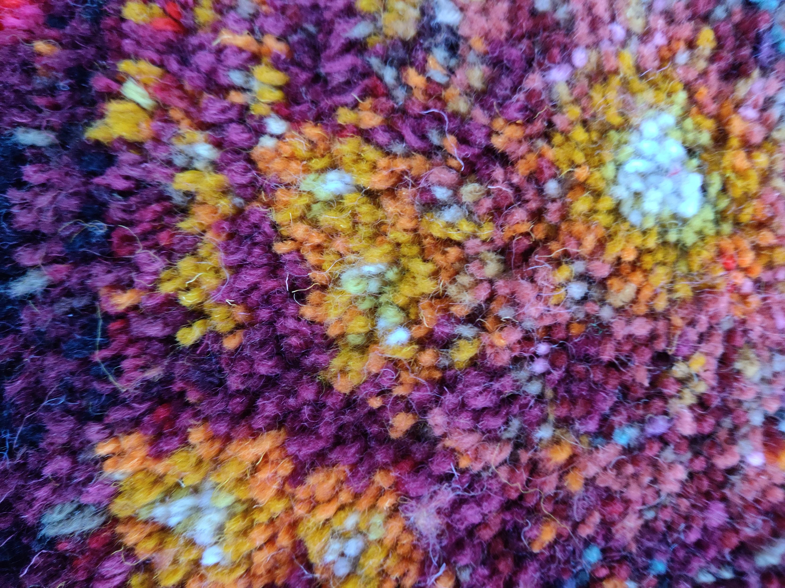 A close up of varicoloured knots on a giant latch hook rug