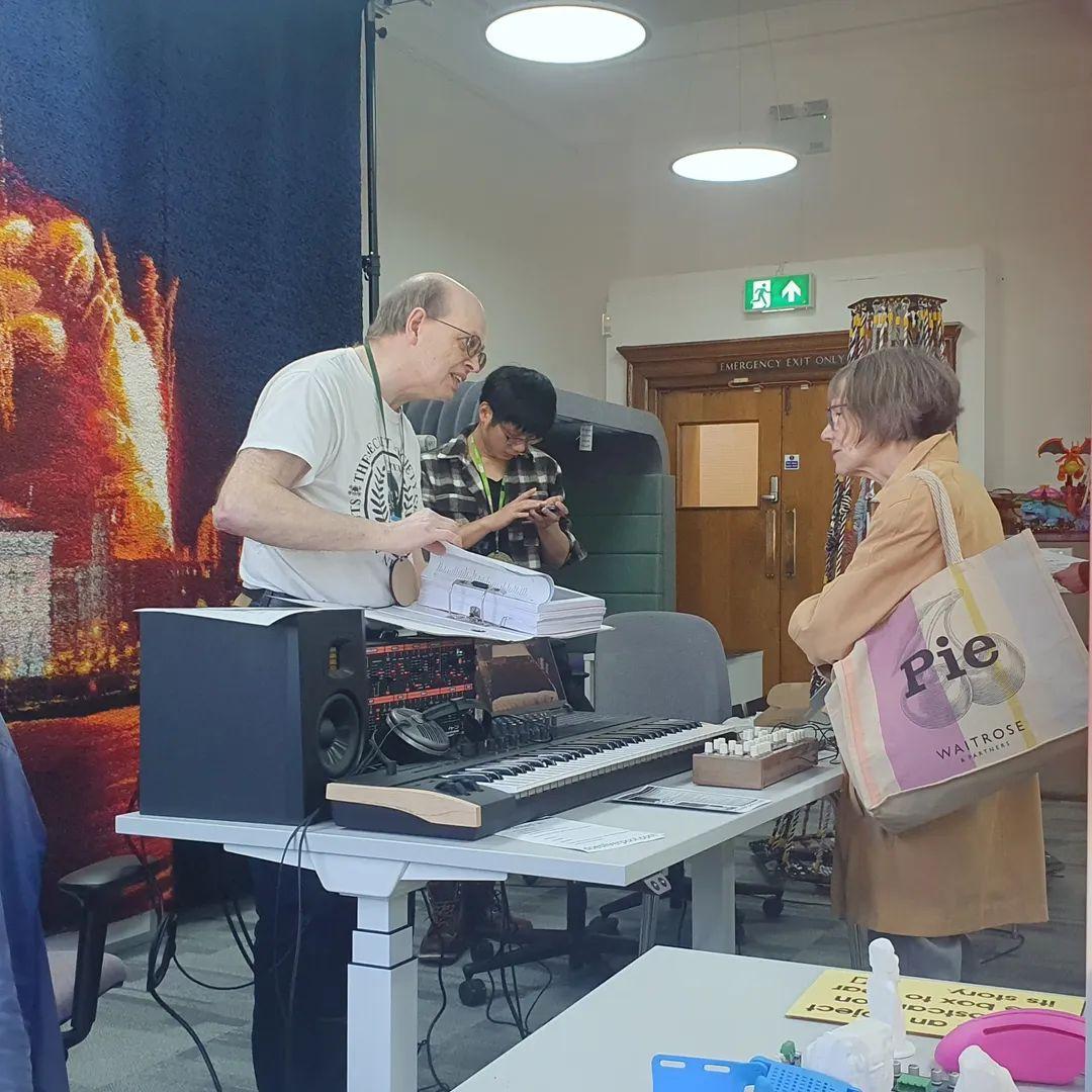 Mike showing the instructions for his Very Large Rug to a MakeFest visitor, while Powei sets up a print on the eufyMake.