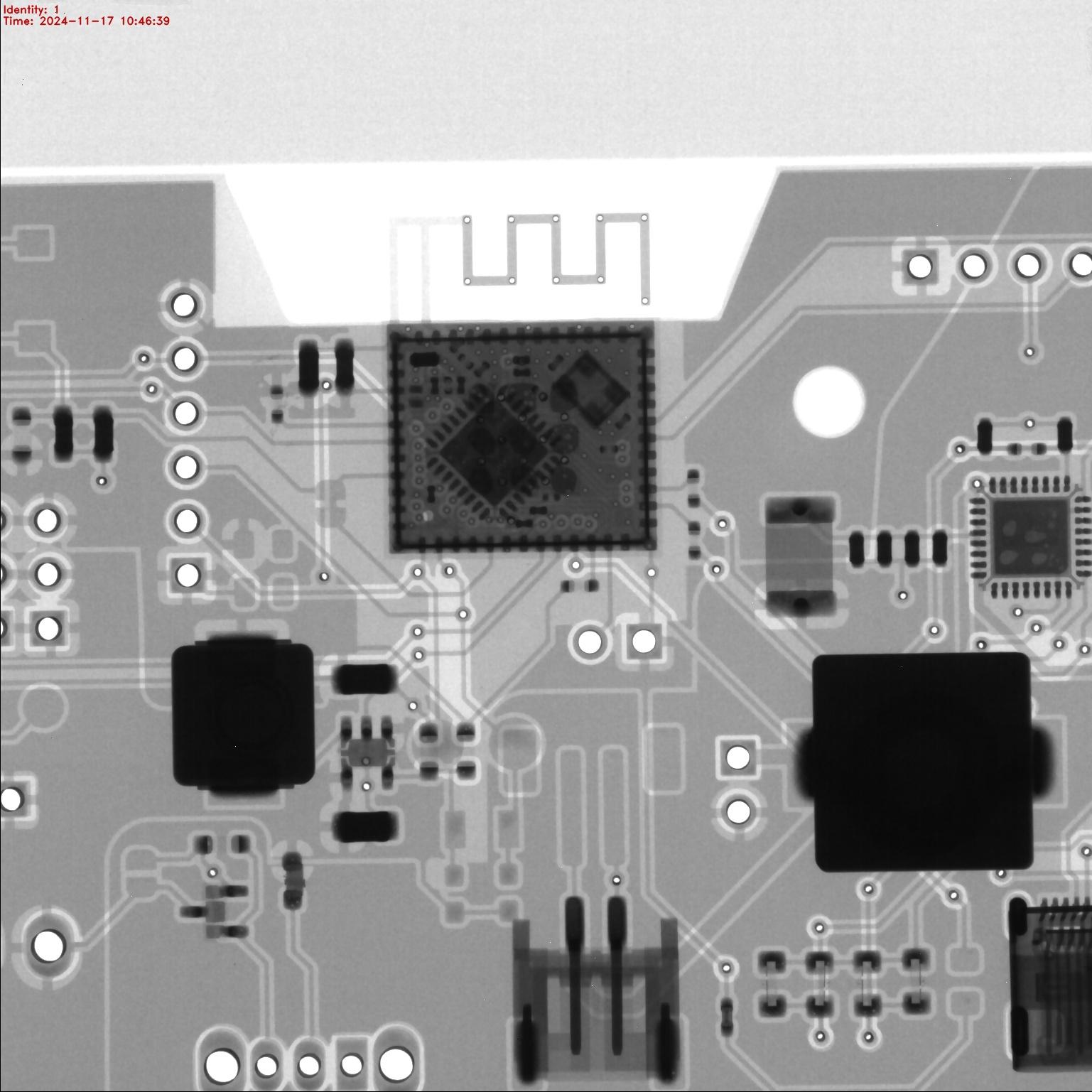 An x-ray of part of a printed circuit board populated with components. You can even see the components inside the metal can of the ESP32-C3 - they're in a darker zone caused by the metal shielding, but can still be made out.