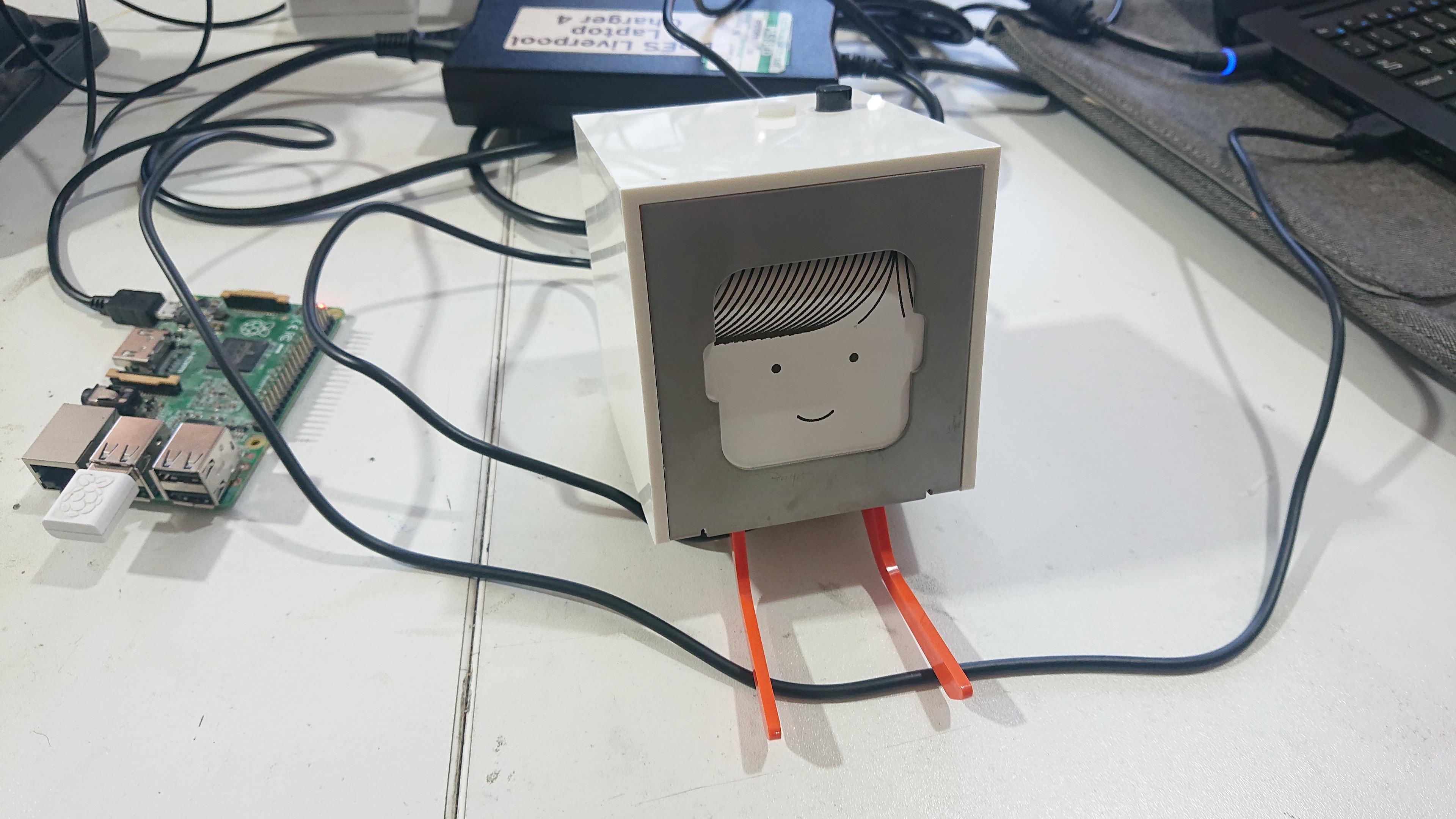 A small receipt printer with a printout of a smiling face sits on a desk