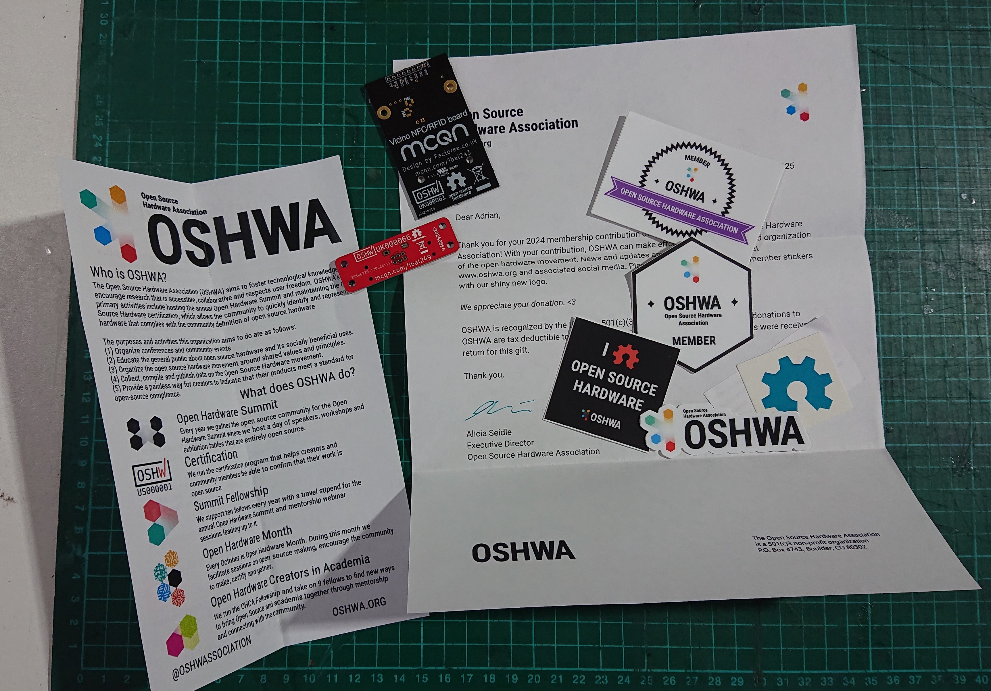 Welcome letter from OSHWA along with some stickers, with two of our OSHWA certified PCBs lying next to them