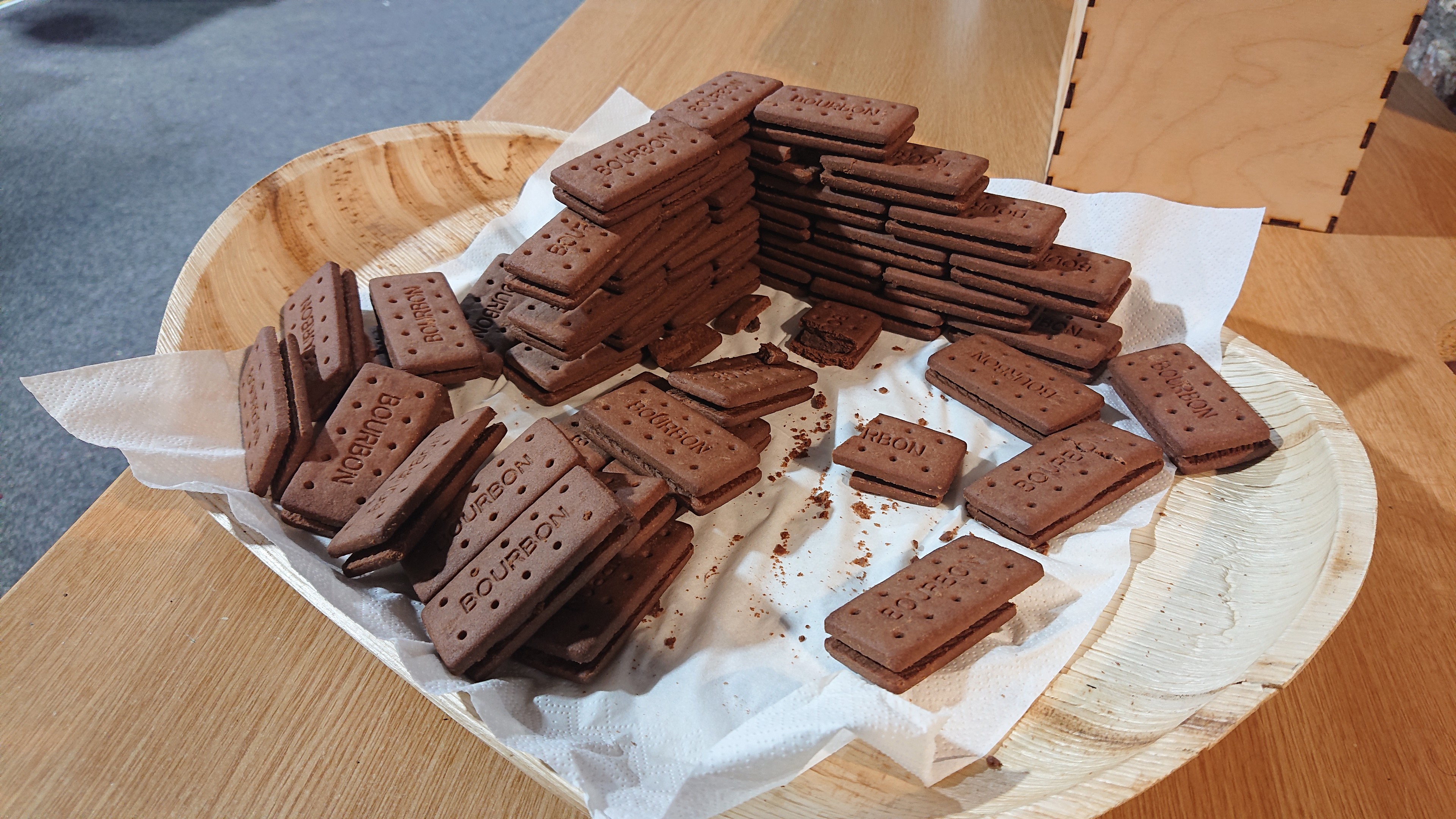A plate containing many bourbon cream biscuits. Given they are broadly brick-shaped, about half of them have been assembled into a wall with a 90 degree corner, six courses high. Stretcher bond, I think