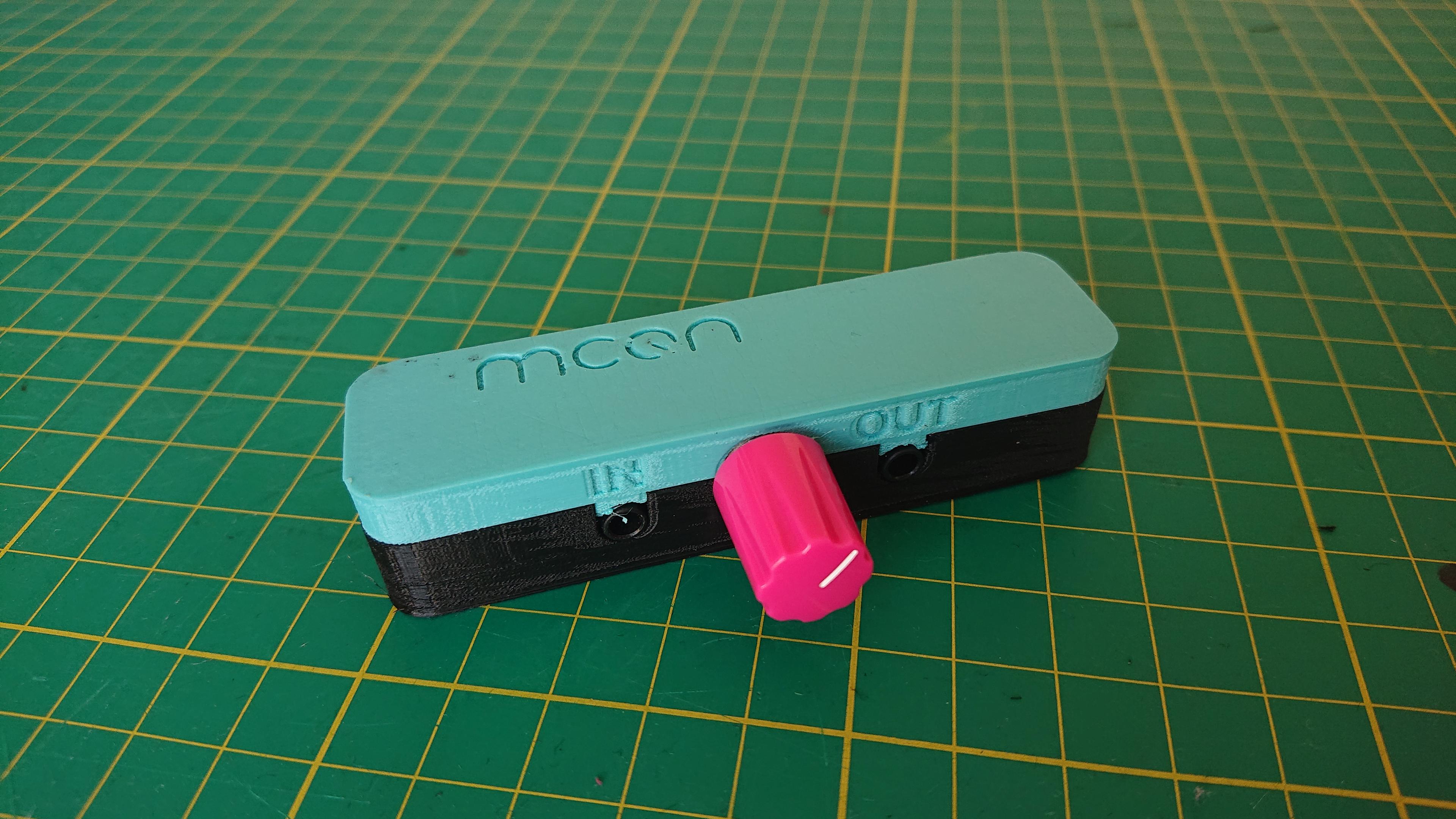 The finished, assembled case. The volume knob is bright pink. Inset into the teal top-half is the MCQN logo on the top, and the 3.5mm audio jacks are labelled 