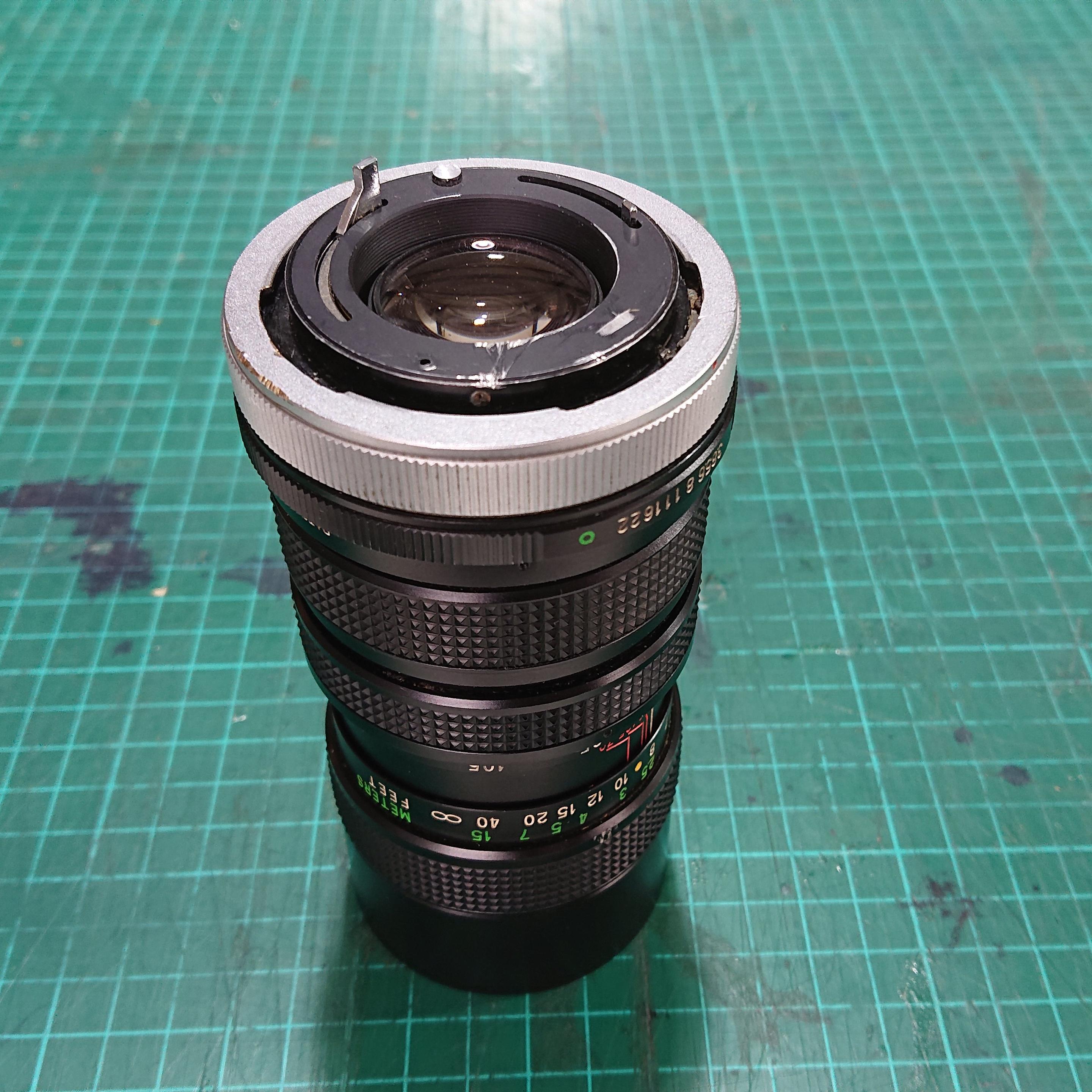 An old SLR telephoto lens, picked up on ebay, sits on a green, well-used, cutting mat.