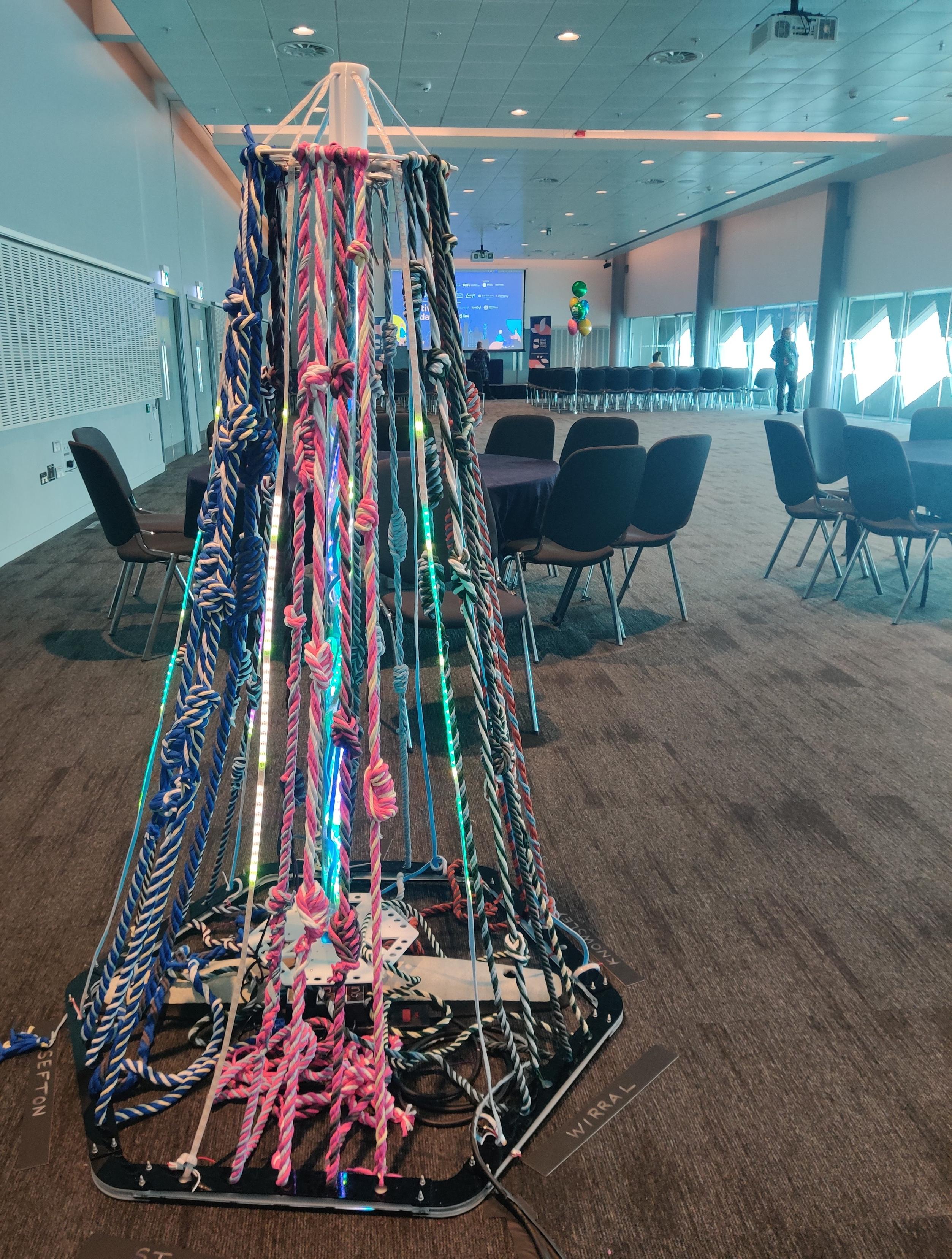 6 sided column with LED and t shirt yarn quipus (knotted cords with recorded numbers). There are 3D printed disks at the top and bottom to separate the cords and attach the LED boards (MCQN MyBikesGotLED boards).