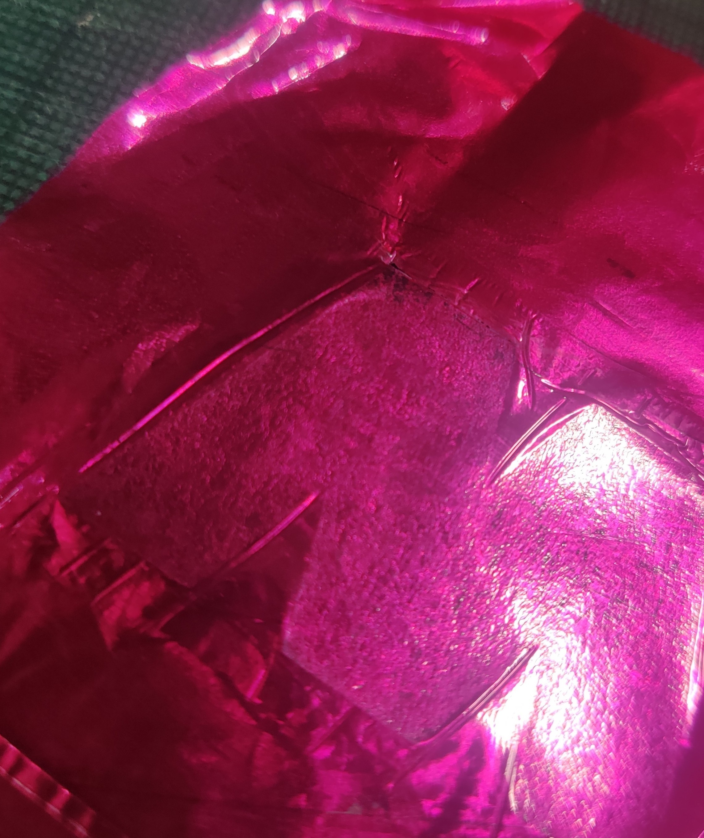 A letter M stuck to the back of a piece of shiny pink hot foil
