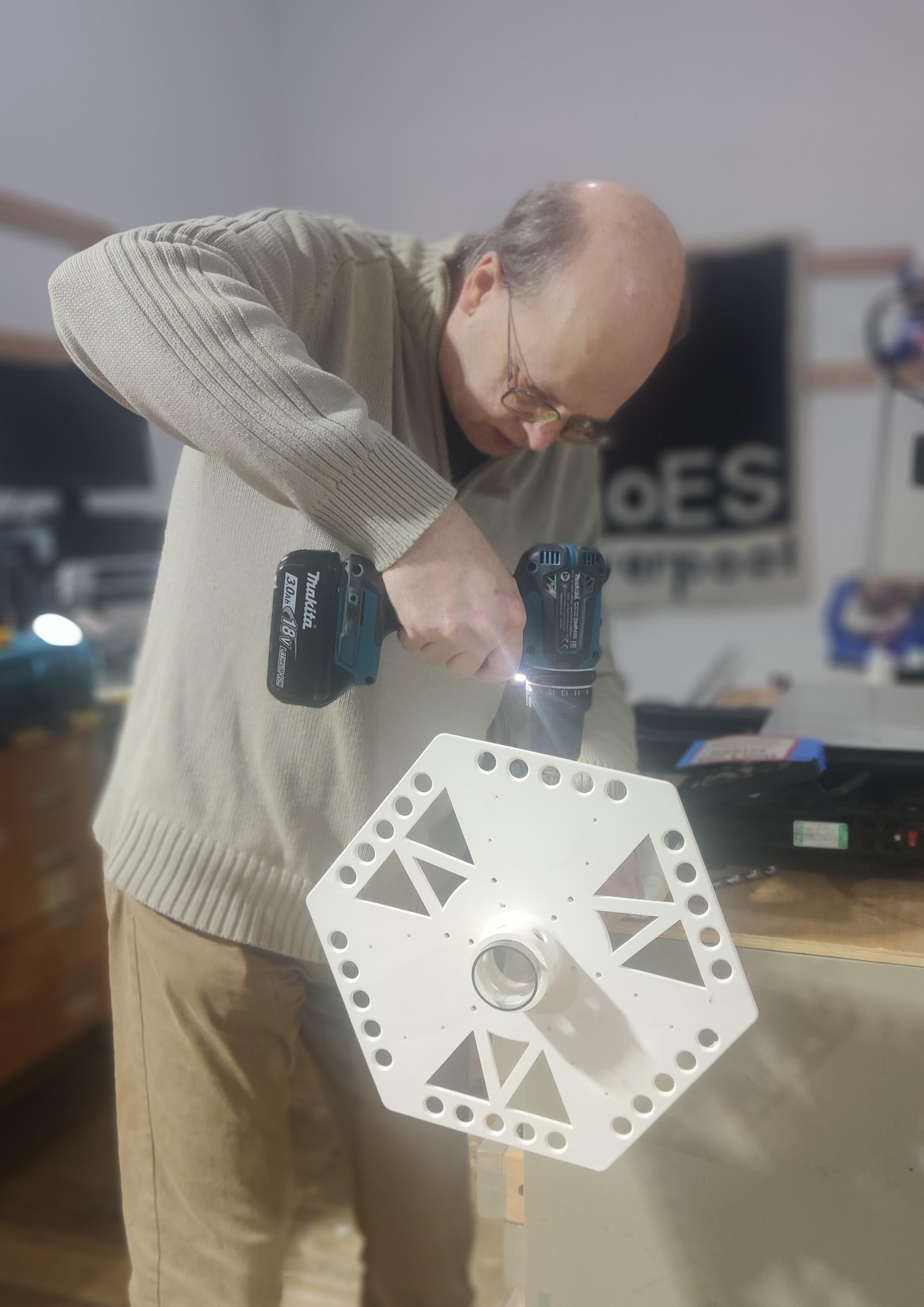 Mike drilling holes in a polycarbonate column to match up with those in a 3D printed hexagon