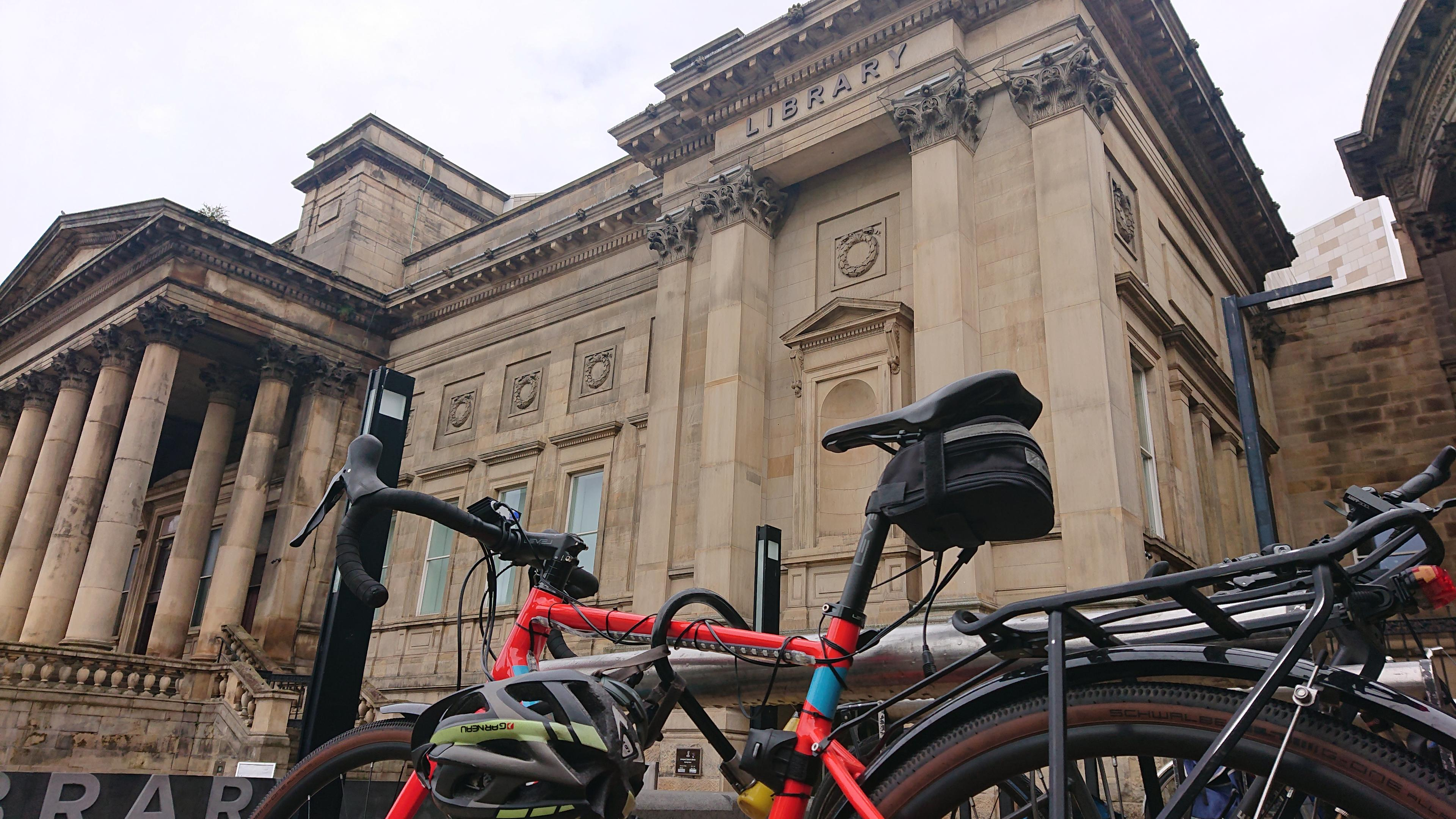 A bike parked up outside the grand neoclassical sandstone central library building.